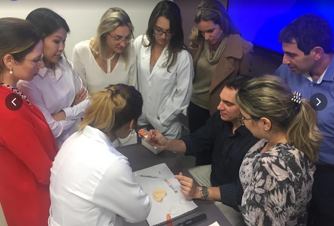 Alunos da ECOE em aula hands-on observando demonstração clínica em modelo odontológico